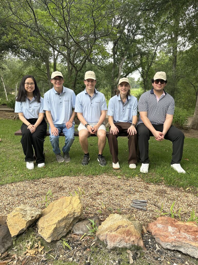 Five StandardData team members on a bench in matching polos and caps